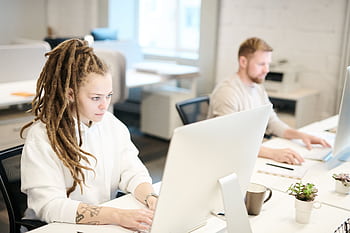 Two colleagues concentrating on work, using computers in a bright modern office. HD wallpaper