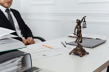 A legal professional's workspace featuring Lady Justice statue, documents, and a laptop. HD wallpaper