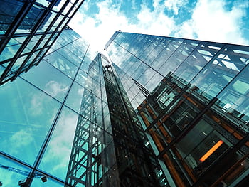 A striking view of a modern glass skyscraper reflecting the sky and clouds. HD wallpaper