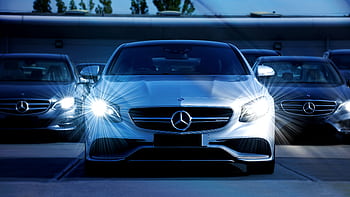 Front view of a lineup of Mercedes-Benz cars with bright headlights, showcasing luxury and elegance. HD wallpaper