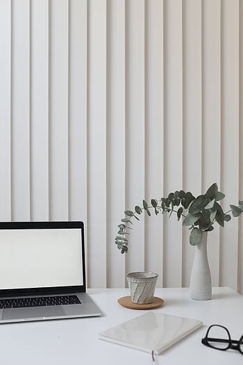 A clean and modern workspace featuring a laptop, vase with greenery, and notepad. HD phone wallpaper