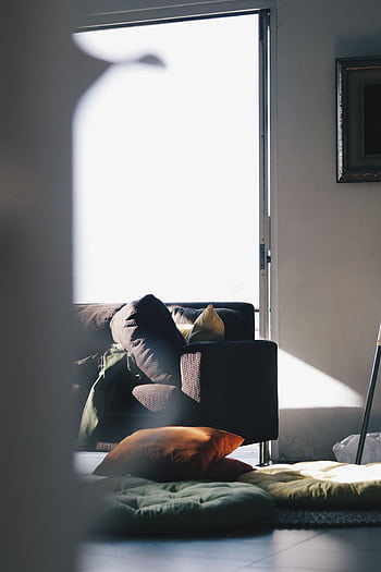 A modern living room illuminated by natural light, featuring a brown sofa and colorful cushions for a cozy atmosphere. HD phone wallpaper