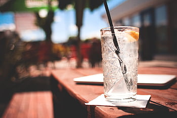 A cold gin and tonic with lemon slice on a summer patio, perfect for refreshment. HD wallpaper