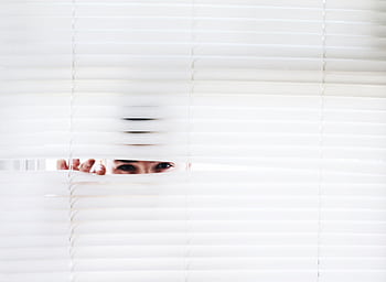 A person peeks through white blinds, creating an intriguing sense of curiosity. HD wallpaper