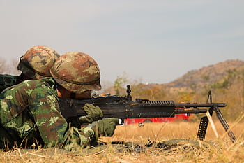 Two soldiers in camouflage uniforms practicing on a field with a machine gun in combat training. HD wallpaper