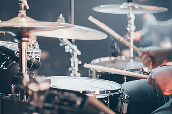 Close-up of a drummer performing on stage with focus on drum set and drumsticks. HD wallpaper