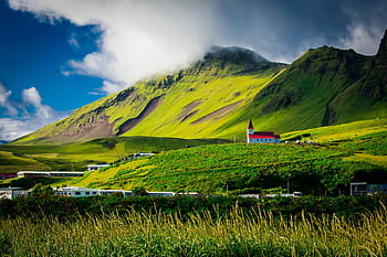 Beautiful landscape of a red-roofed church nestled in lush green hills under a vibrant sky in Iceland. HD wallpaper