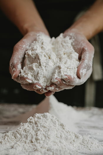 Close-up of a person holding a mound of flour in their hands inside a kitchen. HD phone wallpaper