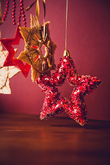 Close-up of shimmering Christmas star ornaments in warm hues, creating a festive ambiance. HD phone wallpaper