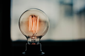 A glowing vintage filament bulb showcasing intricate details of its internal structure. Captivating and artistic. HD wallpaper