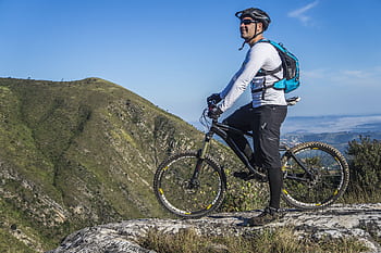 Adult cyclist on mountain bike overlooking scenic rocky landscape under clear blue sky. HD wallpaper