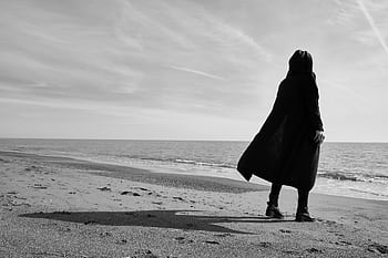 Black and white of a solitary figure on a beach, evoking emotion and solitude. HD wallpaper