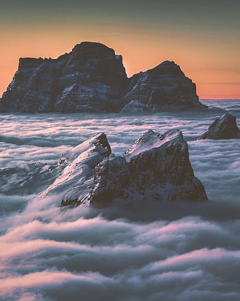 Captivating view of mountain peaks emerging through clouds at twilight, capturing nature's grandeur. HD phone wallpaper