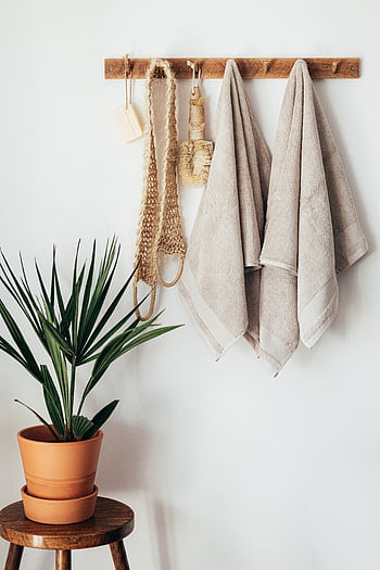 Minimalist bathroom decor featuring towels and a plant, highlighting eco-friendly design. HD phone wallpaper