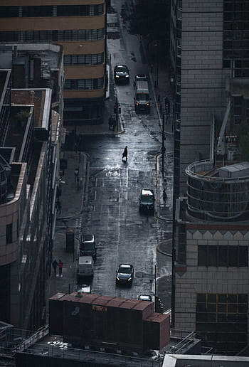 A dark, rainy street view of London with cars and a lone pedestrian under cloudy skies. HD phone wallpaper