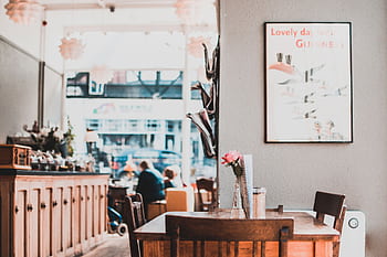 A charming café interior showcasing wooden furniture, warm lighting, and cozy atmosphere. HD wallpaper