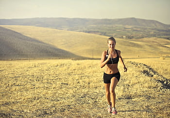 Young woman jogging through a scenic rural landscape under the summer sun. HD wallpaper