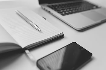 A stylish black and white minimalist workspace featuring a notebook, laptop, and smart. HD wallpaper