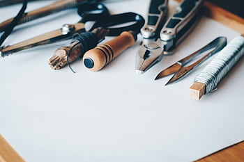 A selection of artisan tools and handmade crafts displayed on a white desk, perfect for creative projects. HD wallpaper