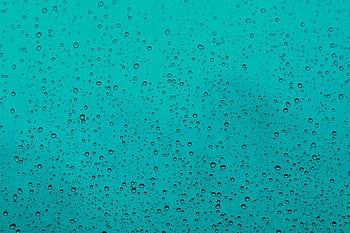 Close-up of water droplets on a teal glass window, capturing the beauty of rain. HD wallpaper