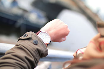A person checks their wristwatch in a hurried outdoor setting, emphasizing time management. HD wallpaper