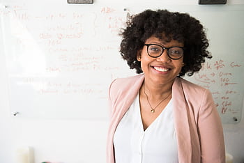 Smiling businesswoman with glasses and afro hairstyle in an office setting. HD wallpaper