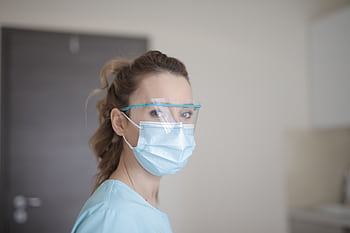 Portrait of a female healthcare worker in protective gear including face mask and shield. HD wallpaper