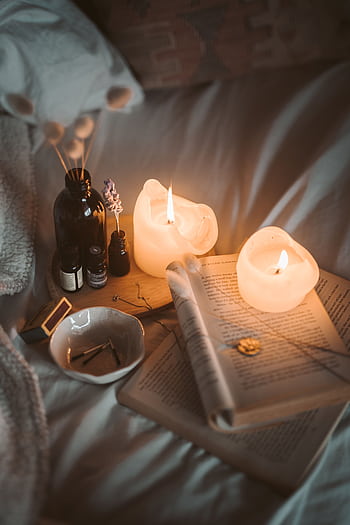 Warm, inviting bedroom setting with candles, books, and soft lighting creating a cozy atmosphere. HD phone wallpaper