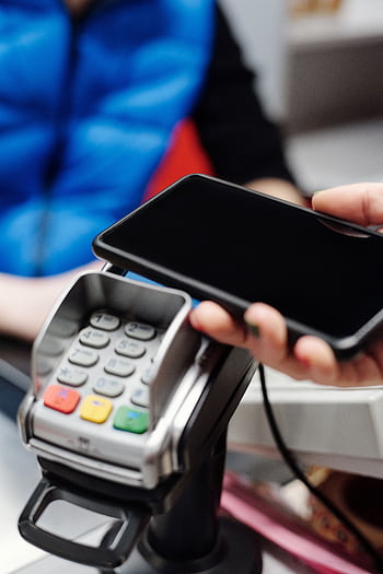 Close-up of a hand making contactless payment using a smart at a card terminal. HD phone wallpaper