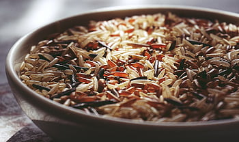 Macro shot of a ceramic bowl filled with colorful mixed wild rice, highlighting textures. HD wallpaper