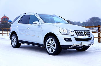 Luxurious white SUV navigating snowy road in winter with scenic background in Scotland. HD wallpaper