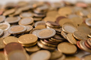 A variety of Euro coins scattered on a flat surface, showcasing different denominations in a warm light. HD wallpaper