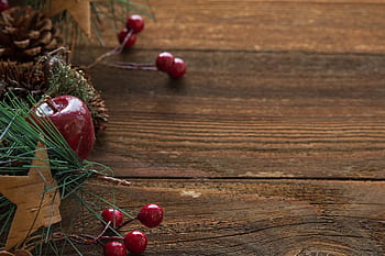 Rustic Christmas decorations on wood table with pine cones and red berries. HD wallpaper