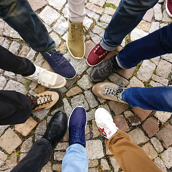 Circle of sneakers on cobblestone pavement representing diversity and urban fashion. HD phone wallpaper