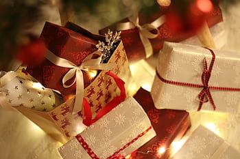 Beautifully wrapped Christmas presents under the tree with festive decorations and ribbons. HD wallpaper