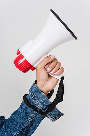 A person in a denim jacket holds a red and white mega, emphasizing communication. HD phone wallpaper