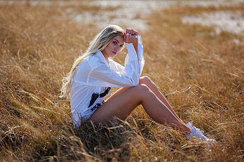 A Girl In A White Shirt Sitting In A Field Gently Locking Eyes With The Viewer, girls, model HD wallpaper