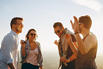 A group of friends laughing and dancing outdoors on a bright sunny day, showcasing friendship and joy. HD wallpaper