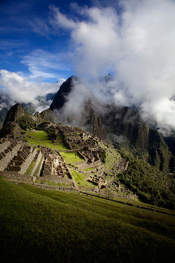 Breathtaking capture of Machu Picchu with dramatic clouds and mountains in Peru. HD phone wallpaper
