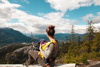 A mother sits with her baby overlooking a scenic mountain landscape, enjoying nature's beauty. HD wallpaper