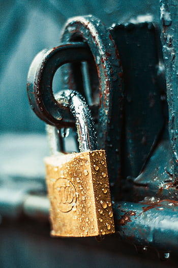 A detailed shot of a wet padlock on a rusty metal surface, showcasing textures and water droplets. HD phone wallpaper