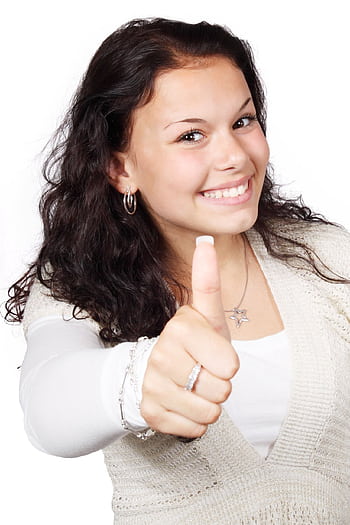 Smiling young woman giving a thumbs up gesture, conveying positivity and approval. HD phone wallpaper