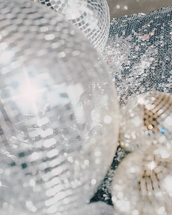 Close-up of shiny disco balls on a sequin surface, creating a festive and luminous atmosphere indoors. HD phone wallpaper