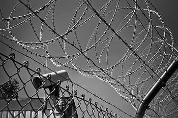 A black and white featuring barbed wire and a security camera, symbolizing protection and surveillance. HD wallpaper