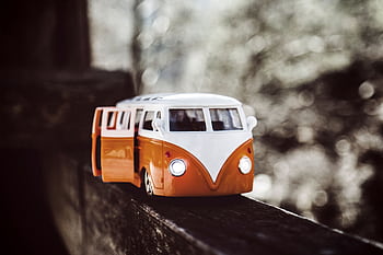 Close-up of a vintage toy campervan on a wooden beam with a bokeh background. HD wallpaper