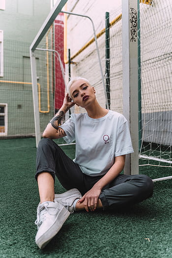 Stylish young woman with tattoos poses casually by a soccer goal in Moscow. HD phone wallpaper