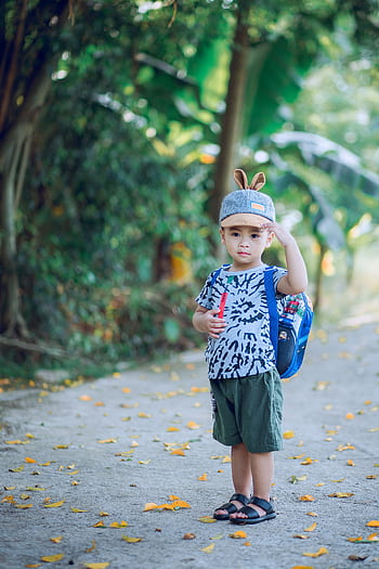 Adorable young boy with backpack enjoying a summer day outdoors, exuding joy and innocence. HD phone wallpaper