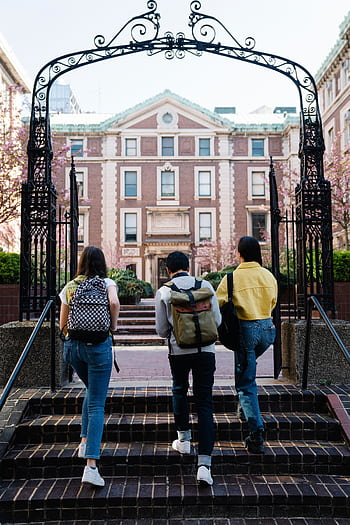 A group of students with backpacks walks towards a university building through an arch. HD phone wallpaper