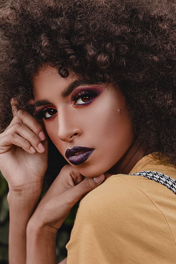 Close-up portrait of a woman showcasing bold makeup and curly hair in an artistic hoot. HD phone wallpaper