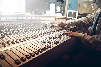 A sound engineer operates a mixing console in a music studio. HD wallpaper